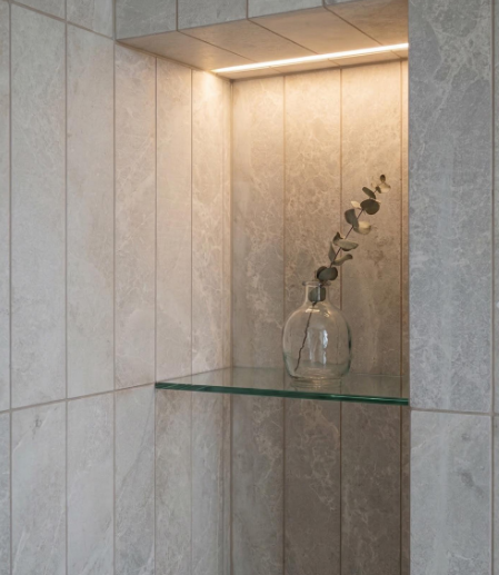 Canto y encuentro de Limepearl en el interior de un nicho de ducha con balda de cristal.