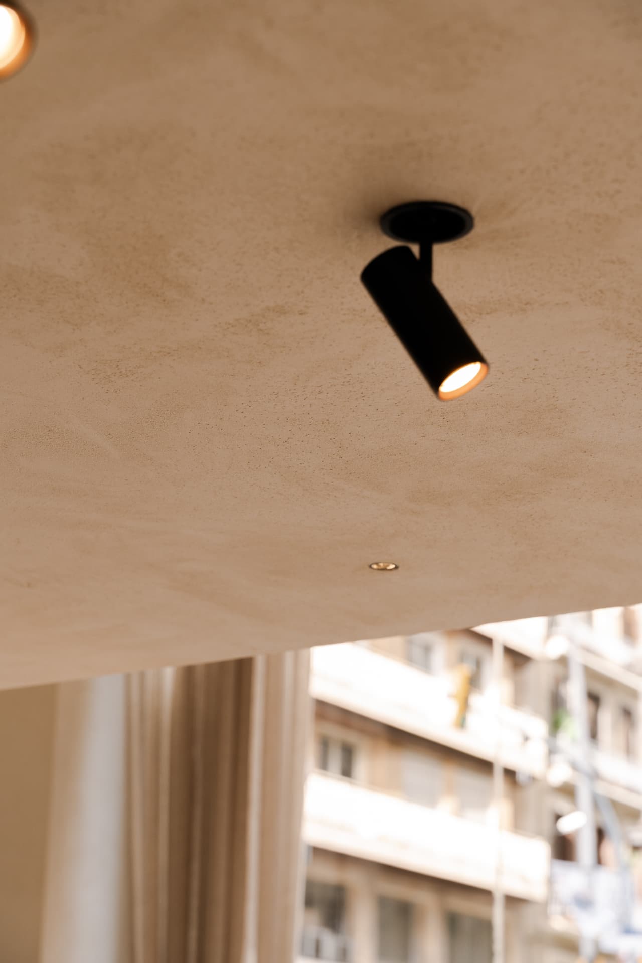 Close view of Limestucco Textured Piedra 10 on the ceiling beside an adjustable spotlight.